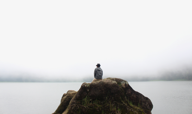 Un homme est assis sur un rocher